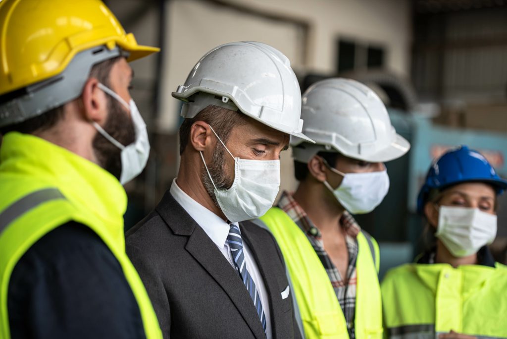 Industrial Manager and Technician, Engineer workers with hardhats, vest discussing Business Management in industry manufacturing Factory. They wear protective face mask for prevention covid 19